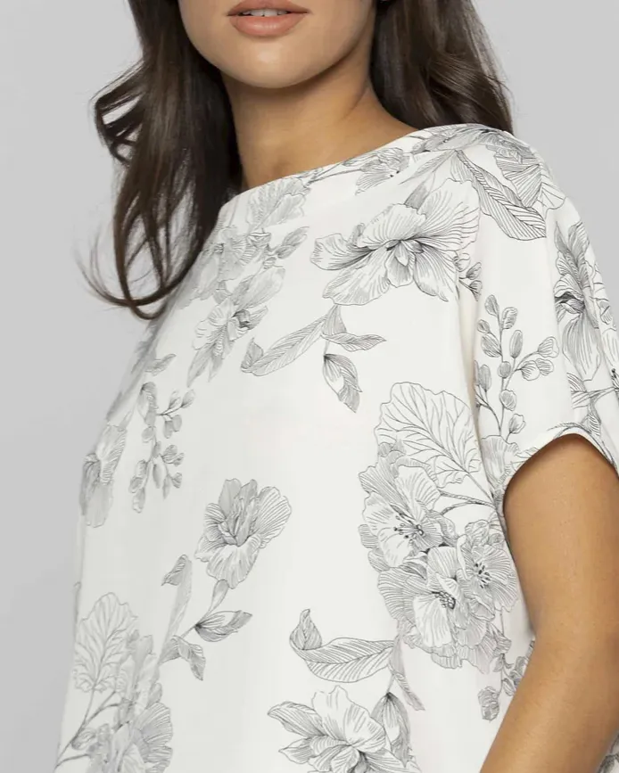 Blusa bianca cropped a fantasia fiori neri con scollo a barchetta e manica scesa